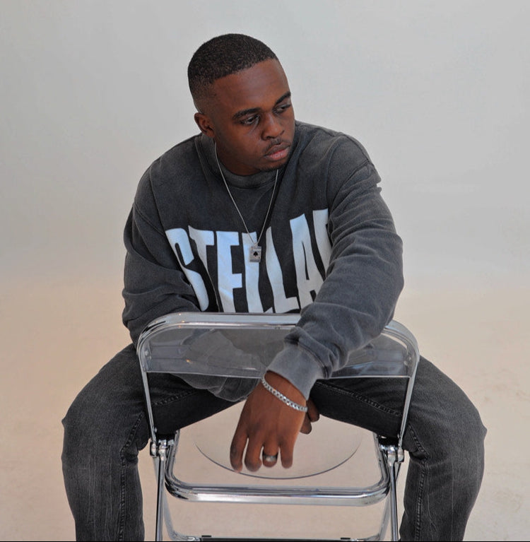 Man sitting on a clear stool against a plain background